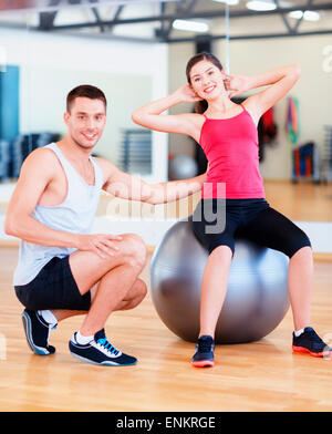 männlichen Trainer mit Frau Crunches auf dem ball zu tun Stockfoto