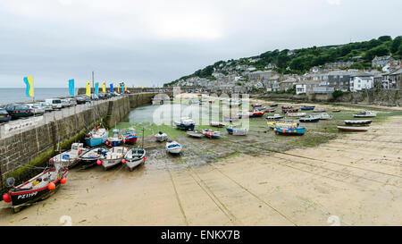 Kornische Fischen Dorf Mousehole mit seinem hübschen Hafen bei Ebbe, wenn die Fischerboote gestrandet sind. Stockfoto