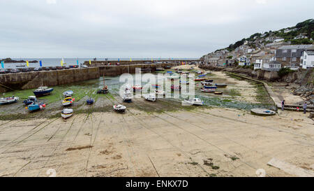 Kornische Fischen Dorf Mousehole mit seinem hübschen Hafen bei Ebbe, wenn die Fischerboote gestrandet sind. Stockfoto