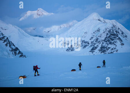 Ein Team von drei Bergsteiger auf ihrem Weg ins Basislager nach erreichen des Gipfels des Mount McKinley, auch bekannt als Denali in Alaska. Mount Hunter im Hintergrund. Stockfoto