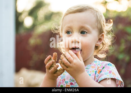 Kleinkind Mädchen Geschmack Sand aus Händen, Chico, Kalifornien. Stockfoto