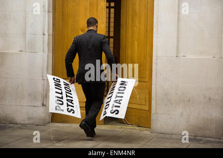 Hackney, London, UK. 7. Mai 2015. Nach einem langen Tag der Abstimmung über die das Land bei den Parlamentswahlen die Wahllokale schließen. Ein Wahllokal Offizier in Hackney Town Hall kuppelt die Beschilderung kurz nach 22:00 Credit: Kristian Buus/Alamy Live News Stockfoto