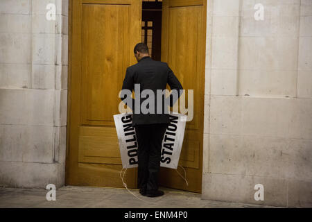 Hackney, London, UK. 7. Mai 2015. Nach einem langen Tag der Abstimmung über die das Land bei den Parlamentswahlen die Wahllokale schließen. Ein Wahllokal Offizier in Hackney Town Hall kuppelt die Beschilderung kurz nach 22:00 Credit: Kristian Buus/Alamy Live News Stockfoto