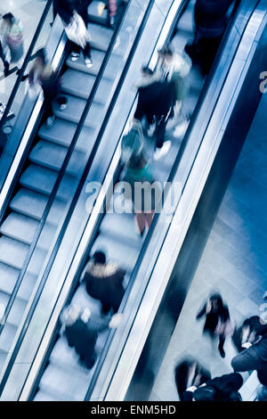 Menschen auf Kreuzung Rolltreppen, blau getönt Stockfoto