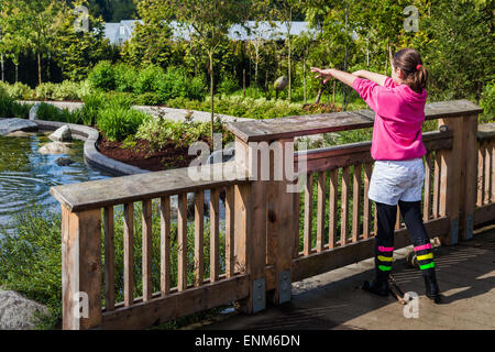 Junge Mädchen werfen einen Stein von einer kleinen Brücke in Vancouver, Kanada Stockfoto