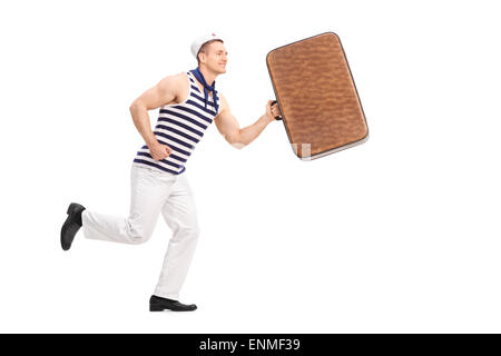 Voller Länge Porträt eines jungen Mannes in eine Seemann Kleidung, isoliert halten eine braune Tasche und läuft auf weißem Hintergrund Stockfoto