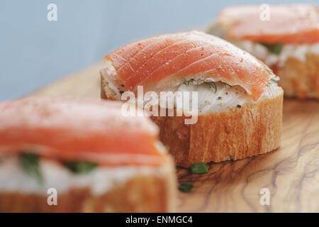 kleine Sandwiches mit Frischkäse und Lachs auf Holztisch Stockfoto