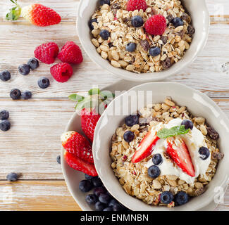 Müsli, frische Beeren und Joghurt zum Frühstück auf einem Holztisch. Stockfoto