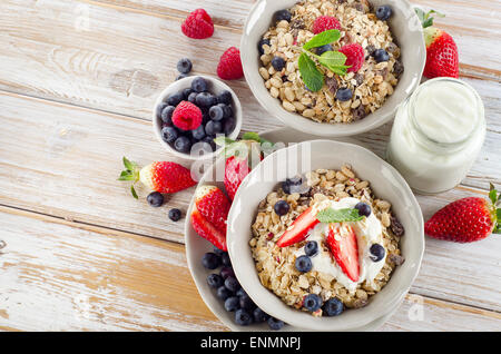 Müsli, reifen Beeren und Joghurt für gesundes Frühstück auf einem Holztisch. Stockfoto