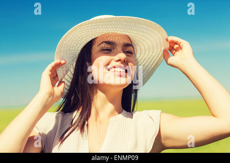 lächelnde junge Frau in Strohhut im freien Stockfoto