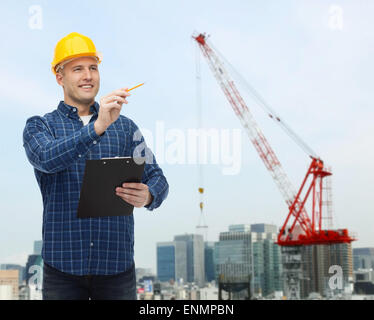 lächelnde männlichen Baumeister in Helm mit Zwischenablage Stockfoto