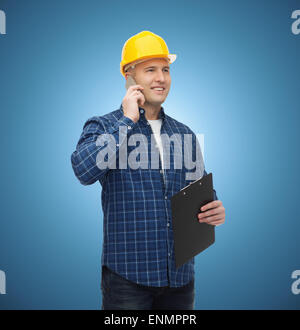 lächelnde männlichen Baumeister in Helm mit Zwischenablage Stockfoto