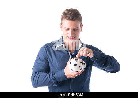 Schöner junger Mann, Münze in Sparschwein, isoliert auf weißem Hintergrund Stockfoto
