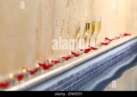 Nahaufnahme von einem Kerzen und Rosenblättern wit einen Champagner-Cups in ein Spa-Feier-Konzept Stockfoto