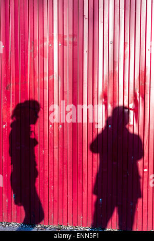 Fotografen, die ein Foto von einer Frau Schattenwurf auf roten Metall Wand Stockfoto