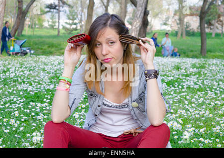 Brach Brunete sitzen im Park unter die Gänseblümchen mit zwei Geldbörsen in ihren Händen Stockfoto