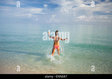 Eine junge Frau läuft in flachen türkisfarbenen Wasser während des Urlaubs in Kuba. Stockfoto