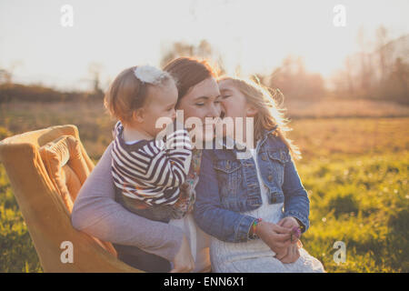 Eine Mutter hält ihre beiden Töchter. Stockfoto