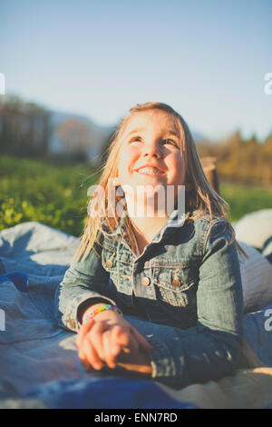 Ein junges Mädchen schaut in den Himmel während der Verlegung auf einer Decke Jean außerhalb. Stockfoto