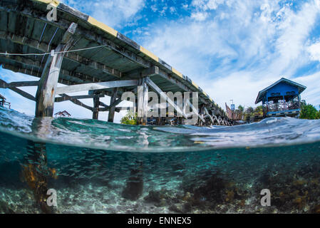 Ein Split-Schuss von der Oberfläche und der Unterwasserlandschaft an Aerbork Vilage Steg in Raja Ampat Stockfoto