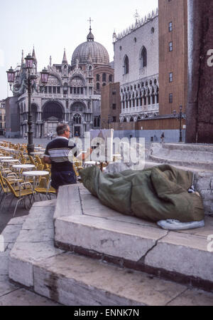 Venedig, Provinz Venedig, Italien. 2. Sep, 1985. In den frühen Morgenstunden ein Künstler an seiner Staffelei auf der Piazza San Marco (Markusplatz) die patriarchalische Kathedrale Basilica malt von San Marco (allgemein bekannt als Basilika Saint Marks) als Atourist neben ihm schläft in seinem Schlafsack. Venedig, ein UNESCO-Weltkulturerbe zählt zu den beliebtesten internationalen Reisezielen. © Arnold Drapkin/ZUMA Draht/Alamy Live-Nachrichten Stockfoto