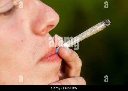 Nahaufnahme Teenager rauchen Marihuana Joint junger Mann rauchender Joint Mann, der Marihuana Zigarette Joint raucht männlicher Teenager, der Cannabis Joint Gesicht inhaliert Stockfoto