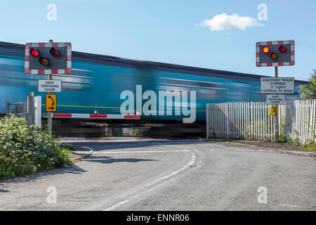 Regionalzug auf der Durchreise eine unbemannte halbe Barriere-Bahnübergang Stockfoto