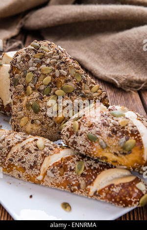 Laugenbrötchen (mit verschiedenen Samen) auf rustikalen hölzernen Hintergrund Stockfoto