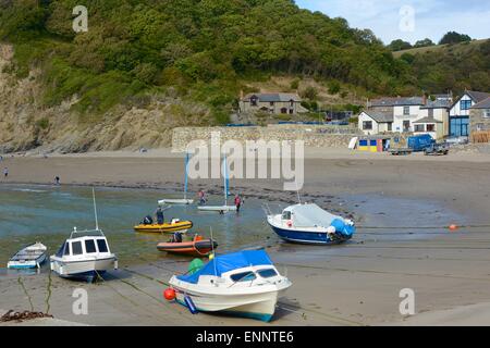 Festgemachten Boote am Polkerris Strand, Cornwall, England. Inn im Hintergrund mit Menschen Stockfoto