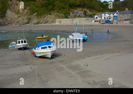 Festgemachten Boote am Polkerris Strand, Cornwall, England. Inn im Hintergrund mit Menschen Stockfoto