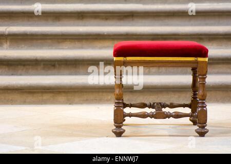 Alte hölzerne Hocker mit roter Sitzfläche und die Treppe im Hintergrund. Stockfoto