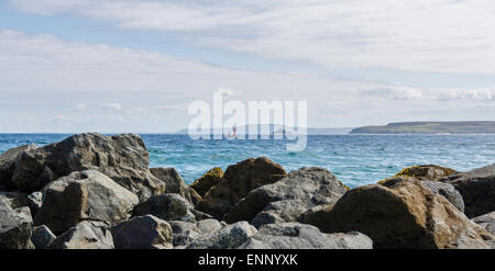 Blick über das Meer in St Ives Bay in Cornwall. Ein Segelboot auf dem Horizont und Godrevy Leuchtturm in der Ferne. Stockfoto