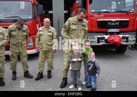 Danzig, Polen 9. Mai 2015 polnischen Feuerwehrleute aus Danzig nach Polen aus Nepal zurück. Polnische Retter nahmen an der Rettungsaktion nach dem Erdbeben in Nepal. Es gab 6 Feuerwehrleute und Rettungshund aus Danzig. Feuerwehrmann mit seinen Kindern steht zwischen den Feuer-Rettungswagen Stockfoto