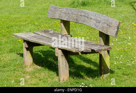Rustikale Holzbank auf dem Rasen in einem Park. Stockfoto