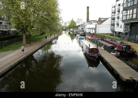 Ein Blick in Richtung Sturts Sperren von Hausbooten günstig in Regents Canal in der Nähe der Schäferin zu Fuß mit einem Jogger Jogging auf dem Leinpfad in der Nähe von City Road im Stadtteil Islington London N1 KATHY DEWITT Stockfoto