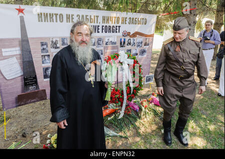 Toronto, Kanada. 9. Mai 2015. Dekan der Heiligen Dreifaltigkeit Russisch-orthodoxe Kirche in Toronto Protopfaffe Vladimir Malchenko steht vor der Gedenktafel mit Bildern und Namen der Kriegsveteranen, während der feierlichen Parade zum 70-jährigen Jubiläum der Tag des Sieges (1945-2015). Tag des Sieges markiert die Kapitulation Nazi-Deutschlands auf die Sowjetunion im zweiten Weltkrieg Teil. Von sowjetischen und dann russische Tradition statt solcher Paraden finden am 9. Mai, wie die sowjetische Regierung den Sieg früh an diesem Tag nach der Vertragsunterzeichnung in Berlin angekündigt. Bildnachweis: Igor Ilyutkin/Alamy Live-Nachrichten Stockfoto