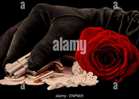 Red Rose auf weißen Handschuh mit Pistole und Kugeln und Hand im schwarzen Handschuh auf schwarzem Samt Stockfoto