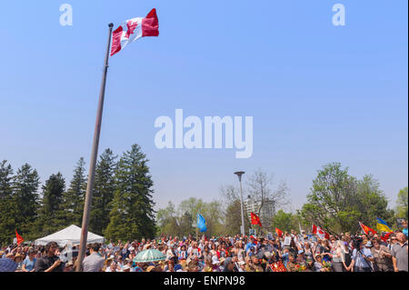 Toronto, Kanada. 9. Mai 2015. Besucher der feierlichen Parade anlässlich 70 Jahre Tag des Sieges (1945-2015) unter erhöhte Flagge Kanadas. Tag des Sieges markiert die Kapitulation Nazi-Deutschlands auf die Sowjetunion im zweiten Weltkrieg Teil. Von sowjetischen und dann russische Tradition statt solcher Paraden finden am 9. Mai, wie die sowjetische Regierung den Sieg früh an diesem Tag nach der Vertragsunterzeichnung in Berlin angekündigt. Bildnachweis: Igor Ilyutkin/Alamy Live-Nachrichten Stockfoto