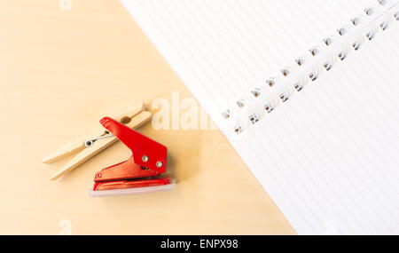 Einzelne rote Locher und Wäscheklammer mit offenen weißen Notebook auf Tischfläche Stockfoto