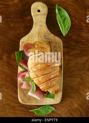 Gourmet-Sandwich Croissant mit Schinken und Basilikum Stockfoto