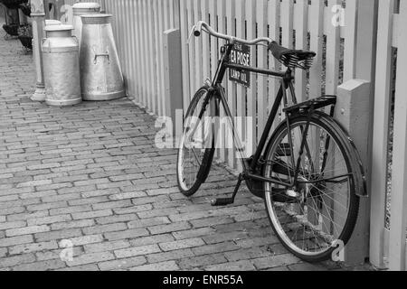 Ein Fahrrad, Geländer, mit Milchkannen im Hintergrund, Bewdley Bahnhof an der Severn Valley Railway gelehnt. Stockfoto