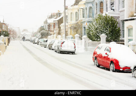 Blick auf die schneebedeckte Straße in Ramsgate in England bei einem Schneefall. Autos geparkt mit Schnee bedeckt, Mann in der Ferne zu Fuß in der Straße. Stockfoto