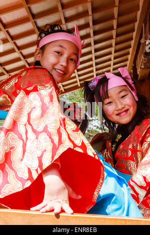 Zwei japanische Kinder, Junge und Mädchen, 7-8 Jahre alt, wandte sich an den Zuschauer und lächelte. Sowohl in Tracht als auch mit Stirnbändern während des Festivals. Stockfoto