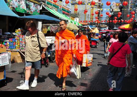 Bangkok, Thailand: Zwei Mönche, gekleidet in ihren leuchtend orangefarbene Gewänder Einkaufstaschen zu Fuß entlang einer Straße in Chinatown Stockfoto