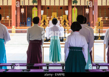 Der Nishinomiya-Schrein in Japan. Shinto Priester, die die Morgenzeremonie durchführen, während sie vor dem Honden stehen, shinden, dem Heiligtum, Stockfoto