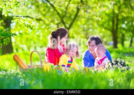 Junge Familie mit Kindern haben Picknick im Freien. Eltern mit zwei Kindern entspannen Sie im sonnigen Sommerterrasse. Stockfoto