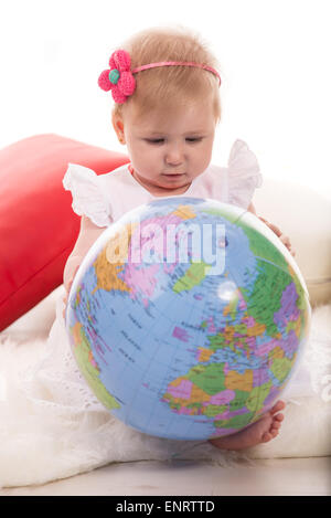 Baby Mädchen Suche auf Weltkugel und sitzen auf flauschige Decke Stockfoto