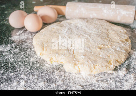 Teig, Eiern und einem Nudelholz auf einer Holzfläche in Mehl bedeckt gerollt Stockfoto