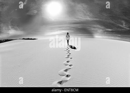 Portugal, Algarve: Frau zu Fuß auf einer Sanddüne in Richtung der Sonne in schwarz / weiß Stockfoto