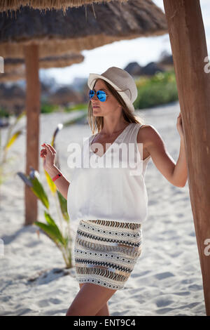 Schöne gebräunte Frau posiert in Sonnenschirm unter Strand Palapa, Sommerurlaub genießen Stockfoto